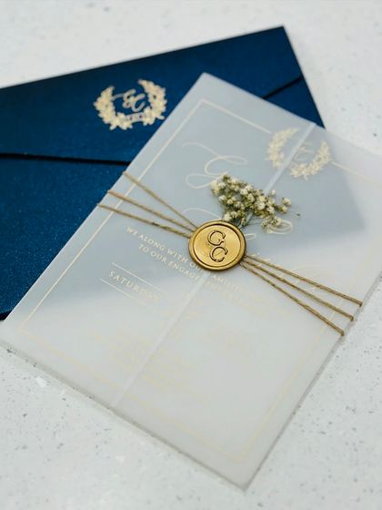 A stunning acrylic wedding invitation with a deep blue envelope. The vellum wrap is tied with twine and finished with a custom wax seal and dried flowers for a luxurious feel.