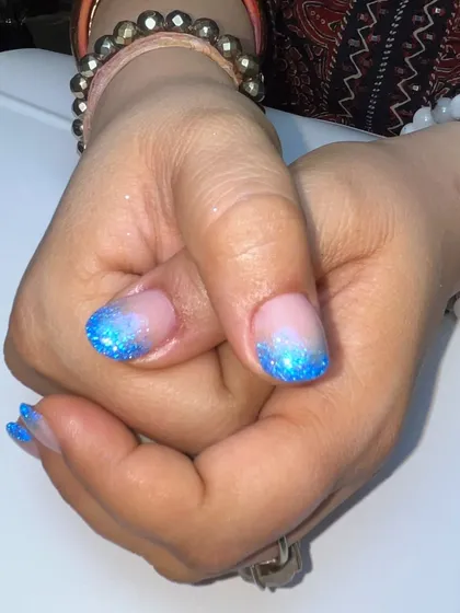 A close-up of the blue glitter tips, highlighting the density of the glitter and the smooth fade into the natural nail base.