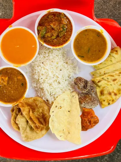 A delicious non-vegetarian thali served at a wedding in Pen. The plate includes chicken curry, paneer sabji, dal, rice, puri, papad, and dessert, offering a complete and satisfying meal.