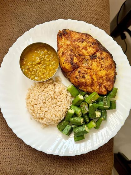 This high-protein plate features a large piece of pan-fried kingfish, served with broken wheat, dal, and sautéed okra.