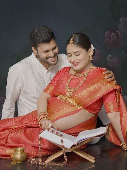 A sweet moment captured during a traditional maternity shoot. The couple is reading a book together, dressed in elegant ethnic wear, creating a portrait that is both cultural and personal.