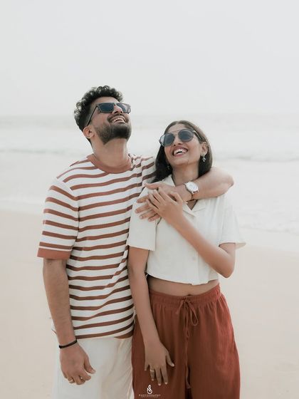 Soaking up the sun and sharing a laugh. Using sunglasses as a prop can add a cool, casual vibe to your beach engagement photos.