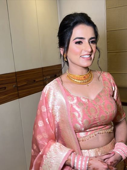 A soft and elegant reception look. The simple gold choker and pink lehenga are paired with a fresh, dewy makeup style.