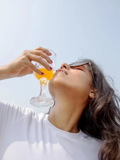A low-angle shot that feels like a classic summer advertisement. The focus on the subject enjoying a drink against the clear sky creates a refreshing and aspirational image for a lifestyle or beverage brand.