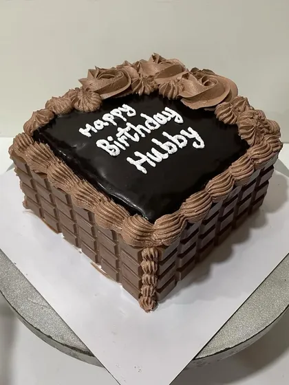 A view of the square chocolate cake on the turntable, showing the basket-weave texture of the chocolate bars.