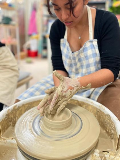 Concentration is key. This student is focused on shaping the walls of her piece, learning to control the clay as it spins.