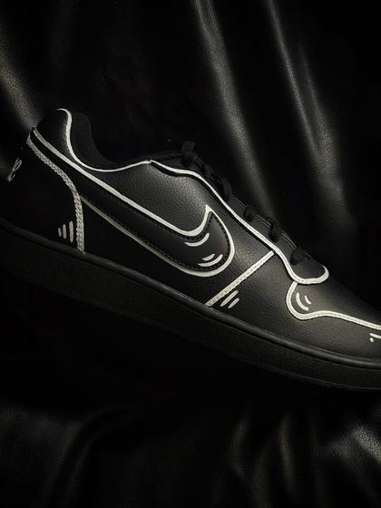 A pair of black Nike Ebernon sneakers with the same bold, white-outline cartoon effect.