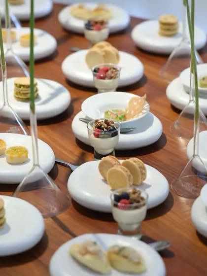 A closer view of the minimalist tablescape, showing a variety of small plates like macarons, parfaits, and savory bites. The arrangement is clean, organized, and visually satisfying.