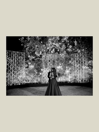 A wide-angle black and white shot of the couple embracing on the dance floor. The dramatic lighting and their solitary figures create a powerful and romantic image.