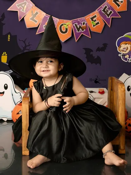 The cutest little witch in town! Her big smile and oversized hat make this Halloween portrait more sweet than spooky.