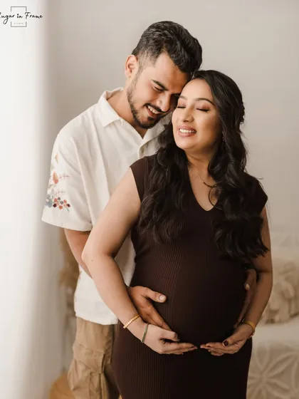 A serene and beautiful maternity photo. The mom-to-be closes her eyes as her partner holds her, capturing a moment of quiet happiness.