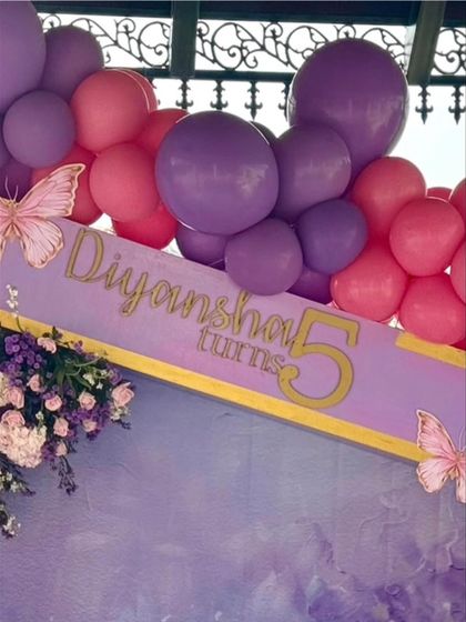 The personalized sign on the backdrop, wishing the birthday girl a happy 5th birthday. The gold lettering adds a touch of elegance to the whimsical theme.
