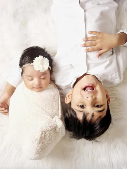 A fun, creative angle for a sibling photoshoot. This top-down shot captures the playful and loving connection between a big brother and his newborn sister.