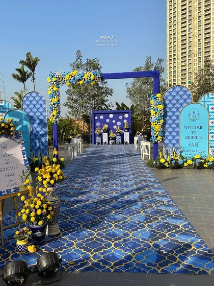 A vibrant and joyful Haldi ceremony entrance, featuring a stunning blue and yellow Moroccan tile theme, complete with floral arches and personalized welcome signs to celebrate your pre-wedding festivities in style.