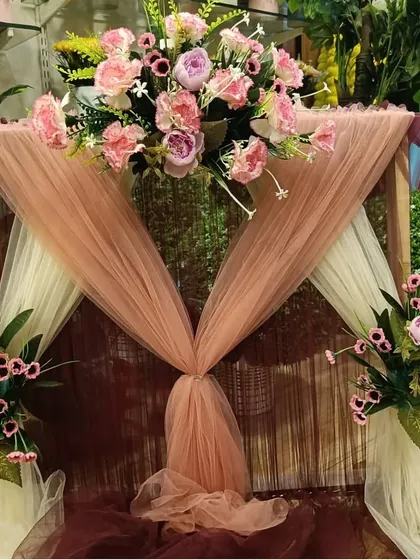 This rustic-chic ready-made decor features a wooden frame, earthy-toned drapes, and soft pink flowers for a warm and inviting setup.