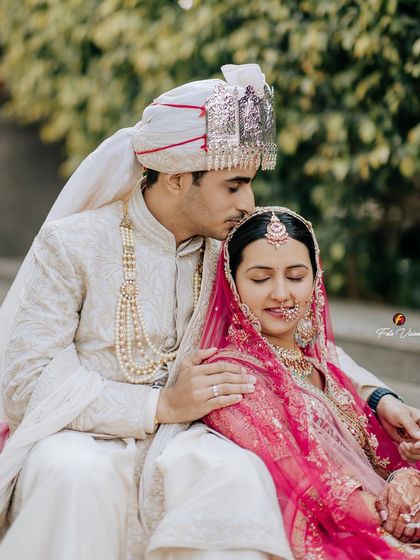 The groom's gentle kiss on his bride's forehead as they sit together, a timeless expression of love and care captured in a quiet moment.