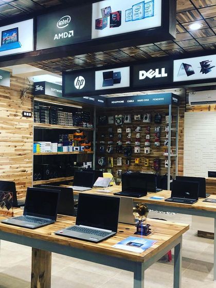 In the RT Computers showroom, we created an industrial-chic vibe with exposed wood paneling and simple metal-frame tables. The overhead brand signage is backlit and clearly organized, making it easy for customers to navigate the store.
