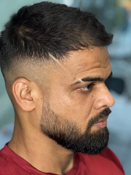 A close-up of a sharp fade with a hair tattoo line and a perfectly shaped beard. It's all in the details.