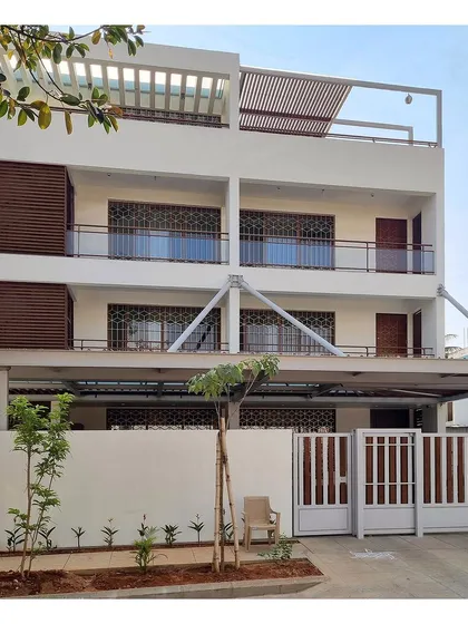 The finished facade of the contemporary residence, showing the interplay of the white structure, wooden screens, and a modern gate design.