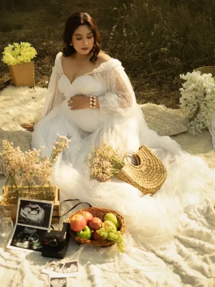 A high-angle shot of the mother-to-be at her styled picnic. Her magnificent white gown spreads out around her, creating a beautiful and dramatic composition.