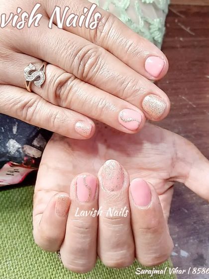 A simple yet elegant design on short, natural nails, featuring a mix of pink polish and a soft gold glitter accent.