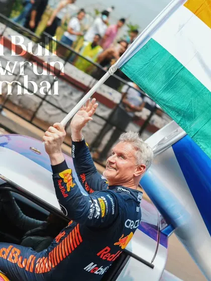An iconic moment with F1 legend David Coulthard celebrating with the Indian flag at the Red Bull Showrun. This is the hero shot, the emotional peak of the event that tells a powerful story and creates a lasting memory.