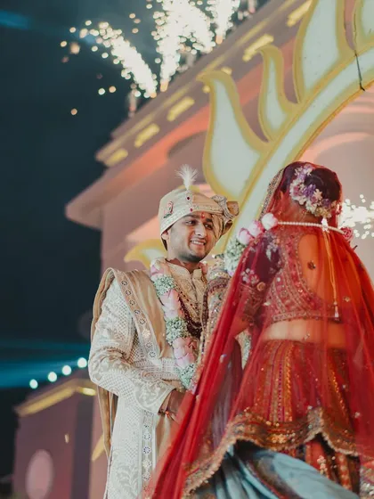 The look of love. The groom smiles as his bride approaches during their grand varmala ceremony, a moment filled with anticipation and joy.