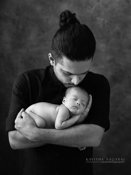 A new dad kisses his newborn's forehead. This black and white portrait is a quiet, powerful tribute to all the fathers who show up with love and patience.