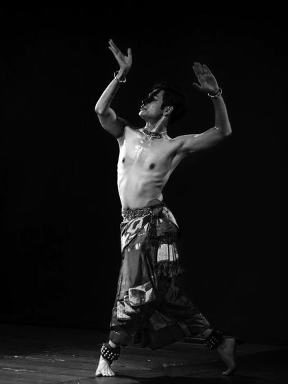 A black and white photograph showing a dynamic pose. The lack of color draws attention to the form, movement, and energy of the dance.