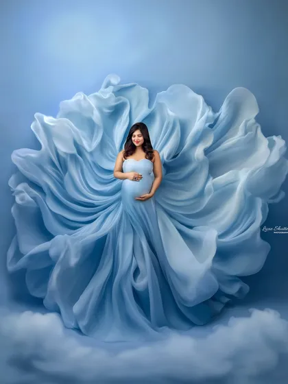 This is the heart of what I do: creating pure magic. This portrait, with its flowing gown blooming like a flower against a dreamy sky-blue canvas, captures the ethereal beauty of motherhood. It’s a perfect example of the fine art style we can achieve in the studio.