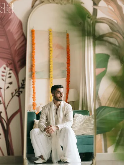 A reflective moment. We used a mirror to frame this thoughtful portrait of the groom, adding depth and an artistic touch to the shot.