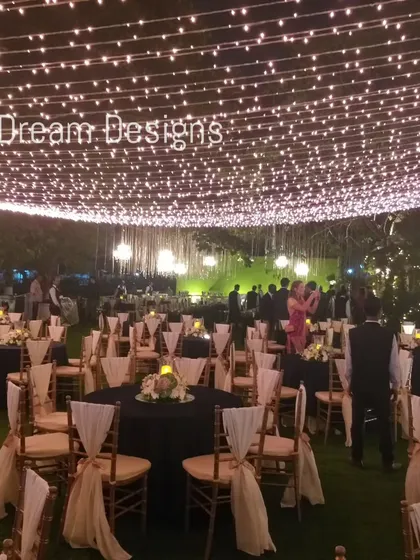 A canopy of fairy lights creates a ceiling of stars for this outdoor reception. The simple yet effective lighting design transforms the entire space into a magical and inviting environment.