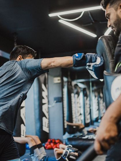 A fighter works on his straight punches with a coach, focusing on extension and accuracy.