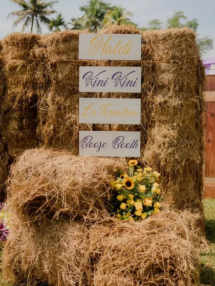 Signage at the entrance of the hay maze, guiding guests to the different zones of the Haldi event: "Haldi," "Kini Kini," "La Tomatina," and the "Booze Booth."