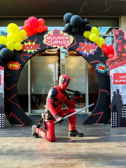 Our Deadpool mascot in a dynamic pose at the entrance of a superhero-themed party, welcoming guests to an action-packed event.