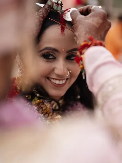 A close-up, intimate moment during the sindoor daan ceremony. The bride's joyful smile as the sindoor is applied is a powerful symbol of her marital union.