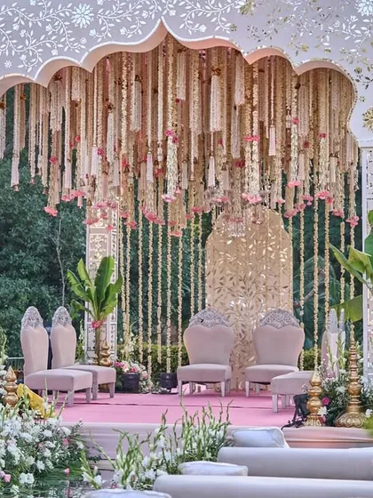 A beautiful view of the pastel-toned mandap through the trees, highlighting its serene and romantic placement within the garden setting.