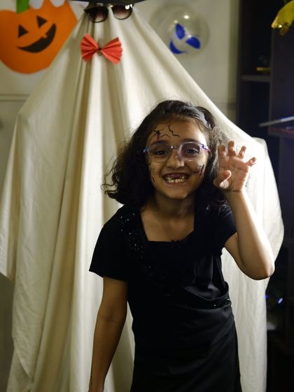 A student showing off her spooky makeup in front of our ghost decoration during the Halloween party.