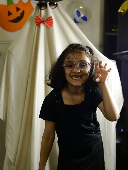 A student showing off her spooky makeup in front of our ghost decoration during the Halloween party.