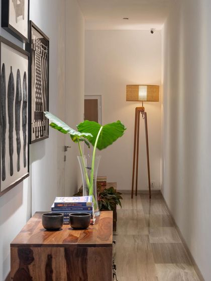 Every corner tells a story. This hallway vignette features a wooden console table, a gallery wall of art, and a tripod floor lamp, turning a simple passageway into a thoughtfully designed moment.