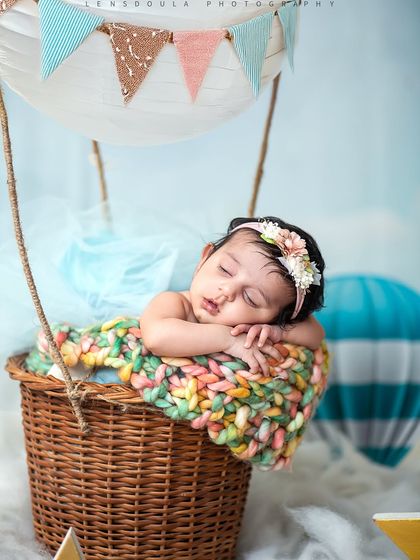 Another angle of our little adventurer, highlighting the delicate floral headband and the colorful blanket she's resting on in her basket.