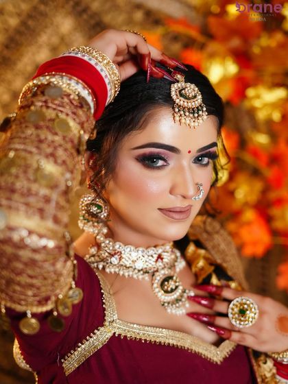This pose highlights the maang tikka and the perfectly defined eye makeup, essential elements of a classic bridal look.