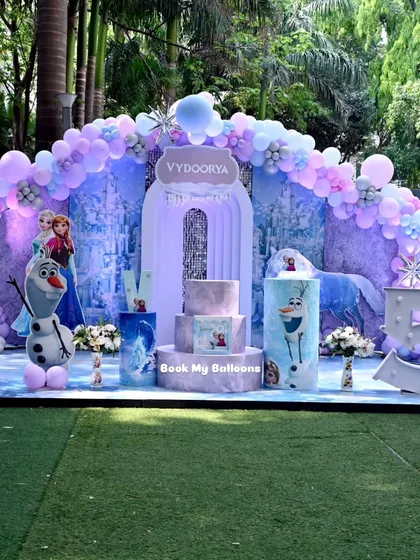 I transform any space into a winter wonderland with our popular Frozen-themed parties. This outdoor setup includes a beautiful balloon arch in icy blues and purples, character cutouts of Elsa and Olaf, and a light-up number '5' for a truly cool celebration.