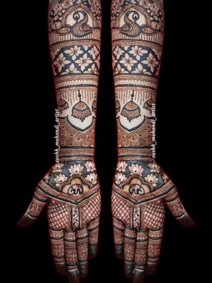 This full bridal design is rich with detail, featuring peacocks, jhumkas, and lotus flowers. The dark, bold lines make the pattern stand out.