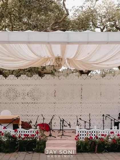 For a soulful Qawali night, I designed a stage that was both elegant and traditional. The backdrop of intricate white latticework, combined with soft draping and a floor lined with red roses, set the perfect mood for the Mehfil-e-Mehendi.