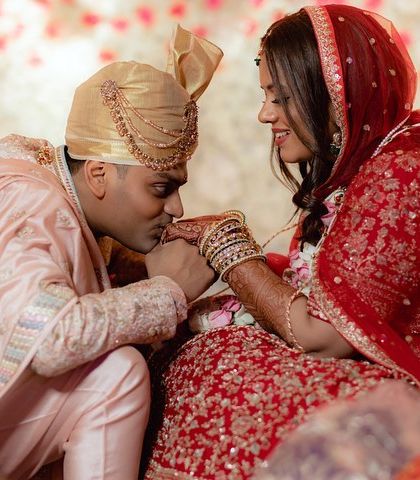 A tender moment between the groom and bride during their Hindu wedding ceremony. The groom's gentle kiss on her hand is a gesture of love and respect.