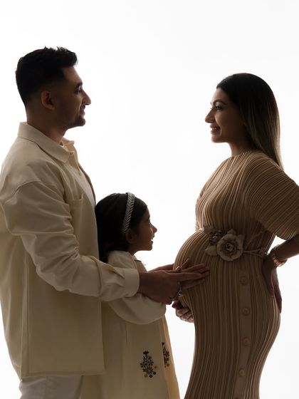 A classic silhouette portrait of the growing family. The soft light and their connected poses create a timeless and artistic maternity photograph.