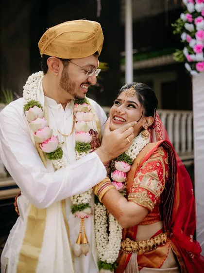 The groom gently touches the bride's cheek in a moment of pure affection, their smiles reflecting the joy of the wedding ceremony.