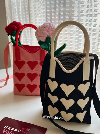 A closer look at the black and pink heart tote bags, paired with crochet flowers.