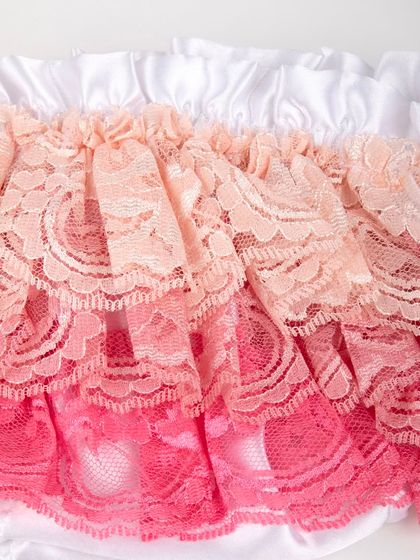 A macro shot of the delicate, layered lace on the ruffled diaper cover.